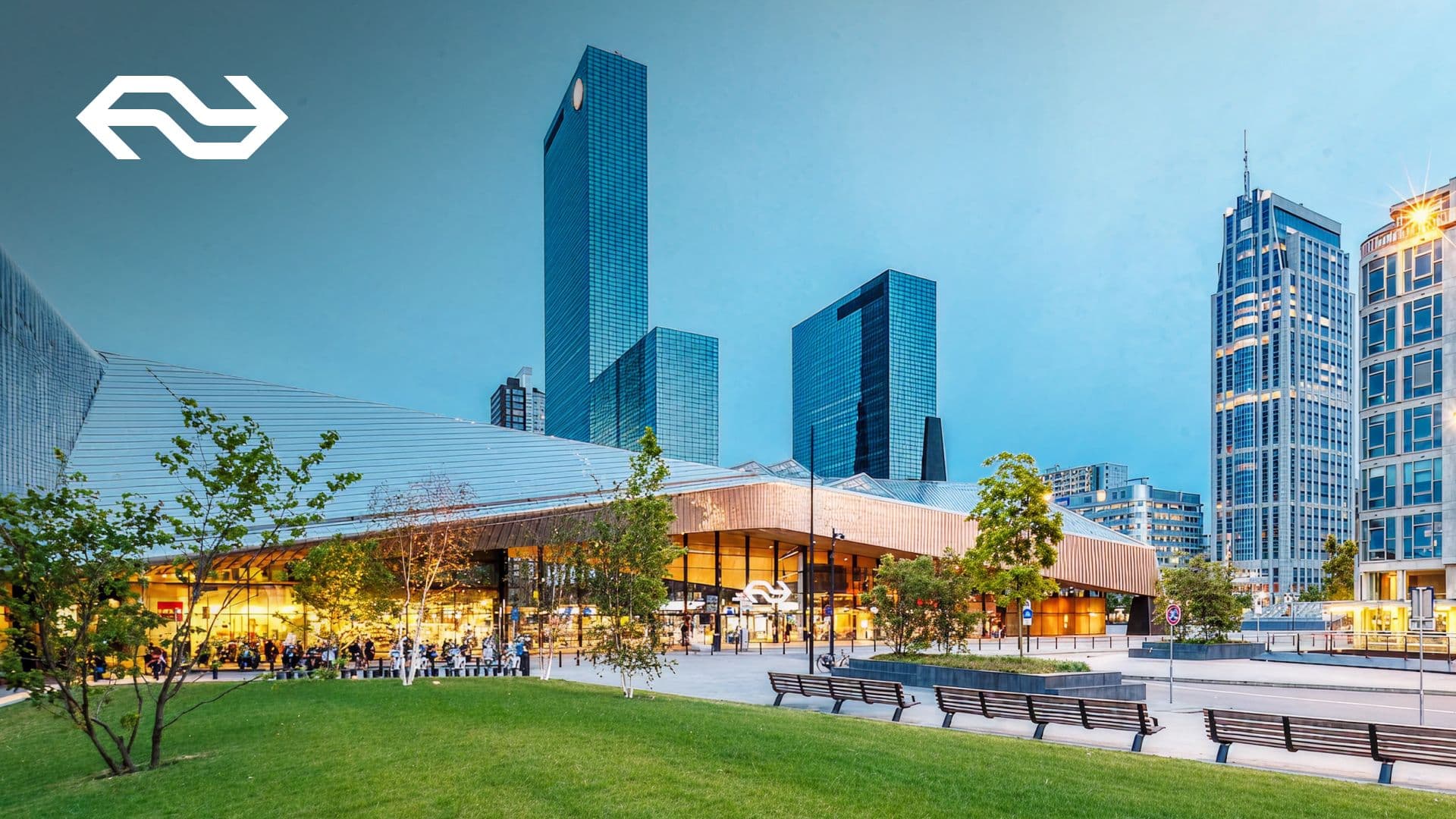 Train station exterior at dusk with city skyline