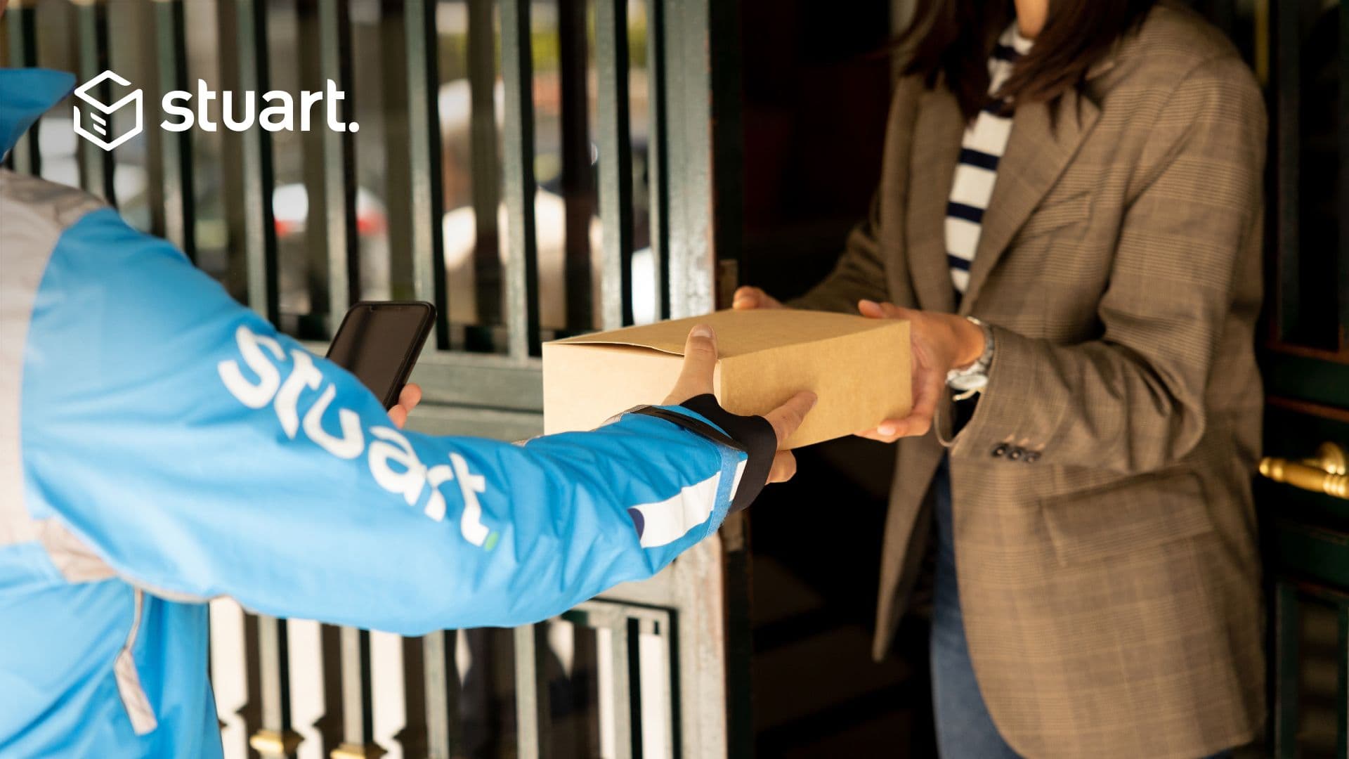 Un coursier Stuart remettant un colis à une femme