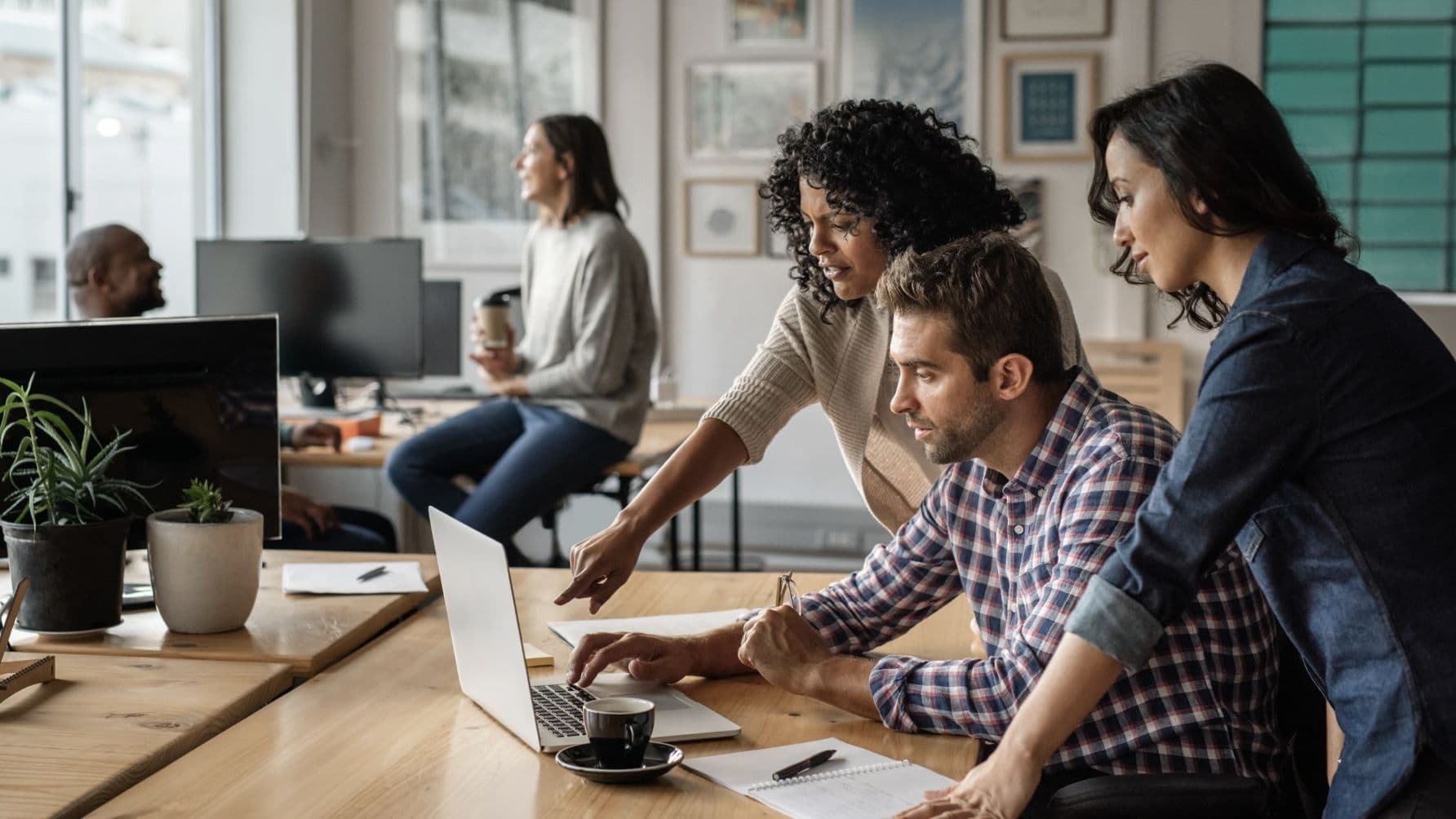 people in an office discussing something while looking at the laptop