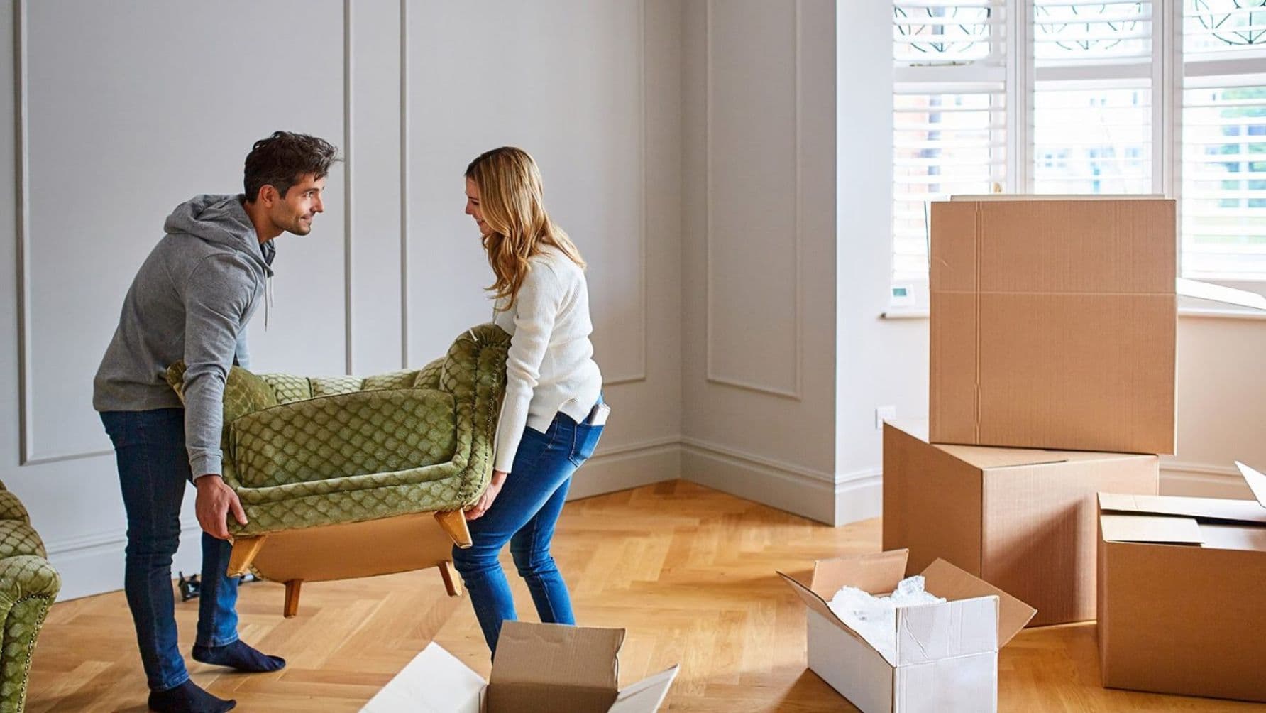 A man and woman carrying a seat trying to setup a room