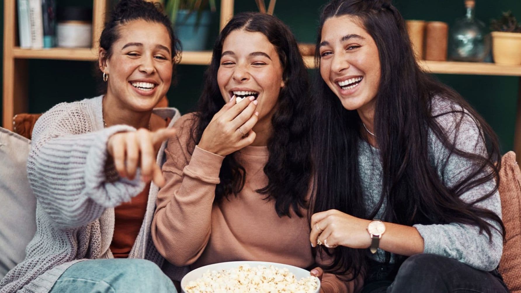 Three ladies eating popcorns while watching