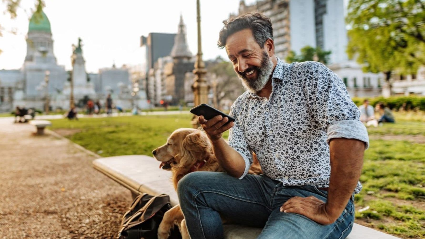 Man with the dog using smart phone on the bench