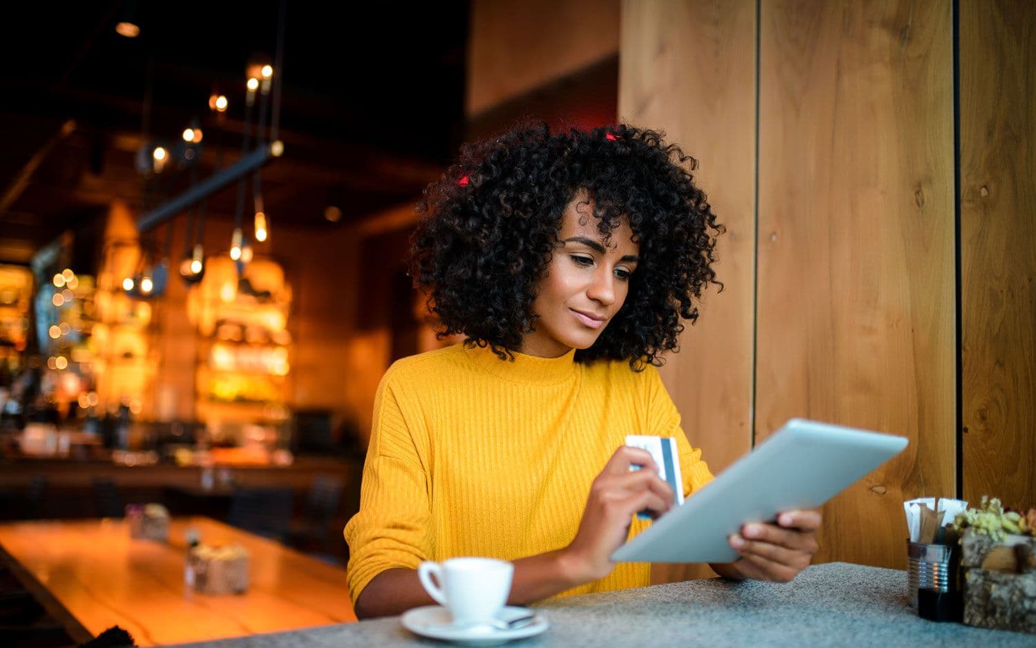 Woman sitting in coffee shop making purchase from Predictive Marketing