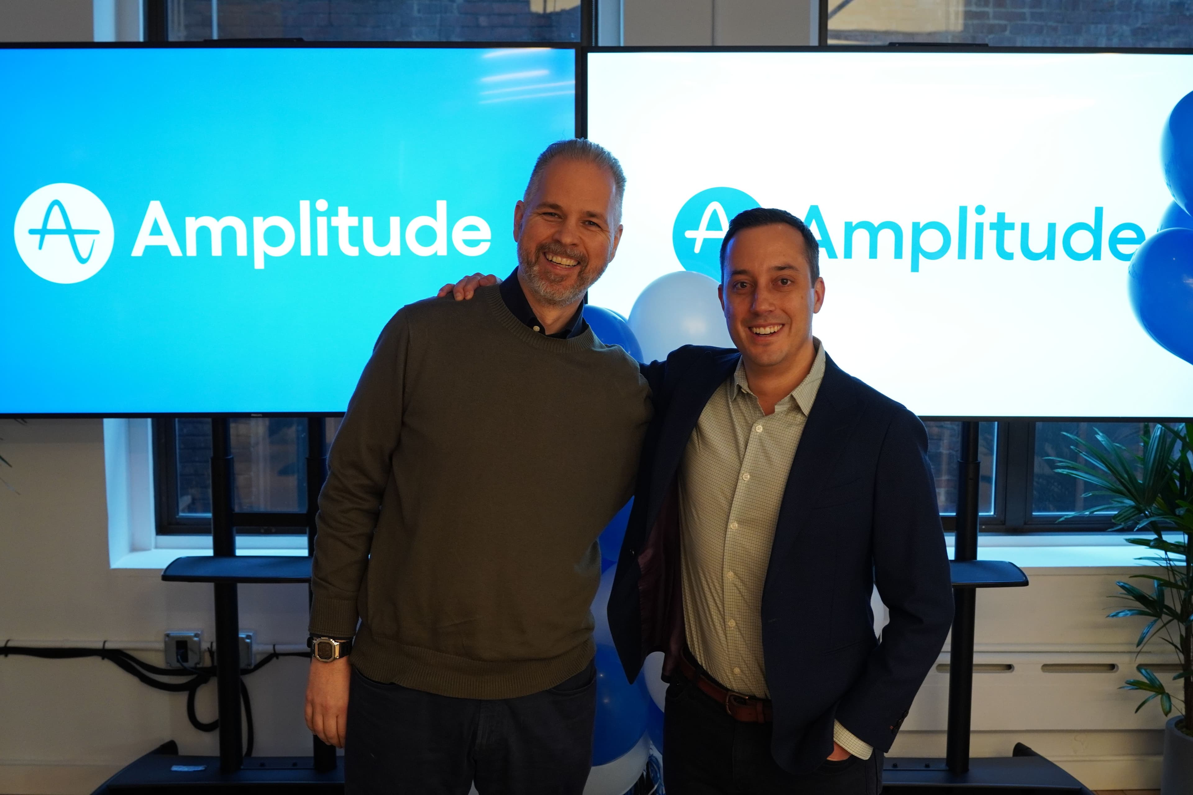 Brian Ivanovick and Brian Wagner smile in front of Amplitude screens
