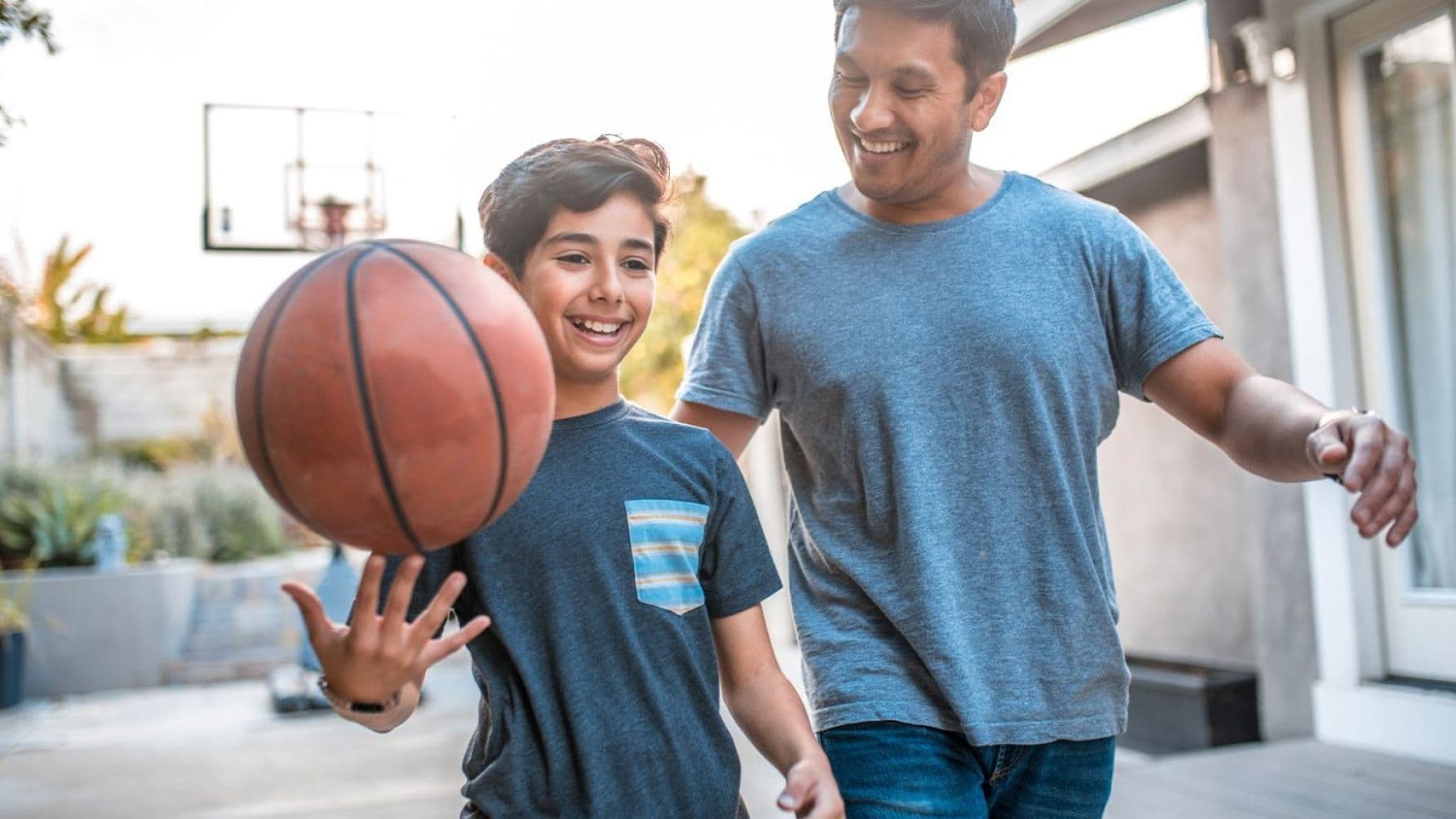 A joyous man accompanied by a young boy, happily strolling along with a ball in tow