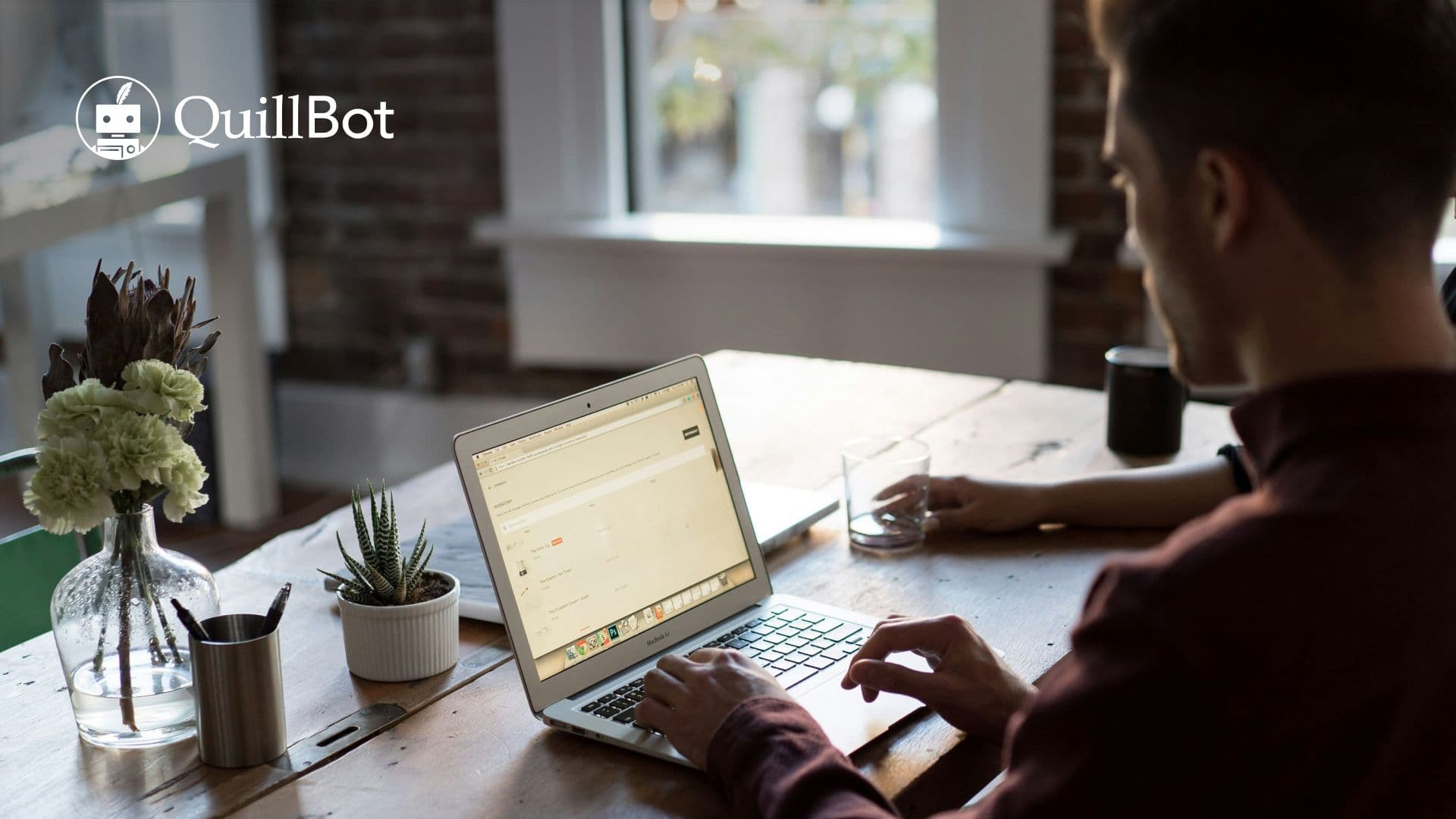 Quillbot usage: A man types on a laptop at a wooden table