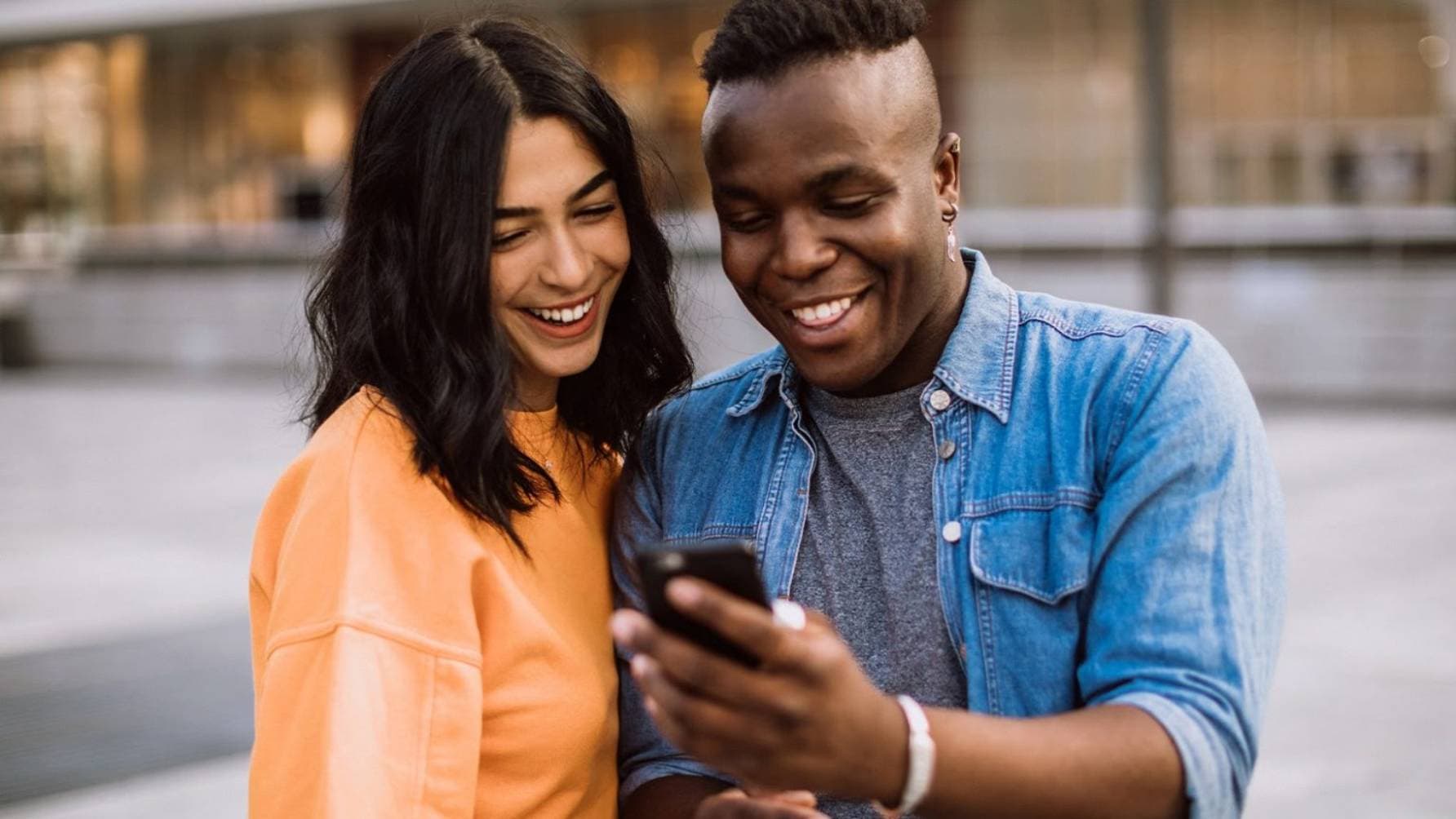 Man and a lady watching something on the phone while smiling
