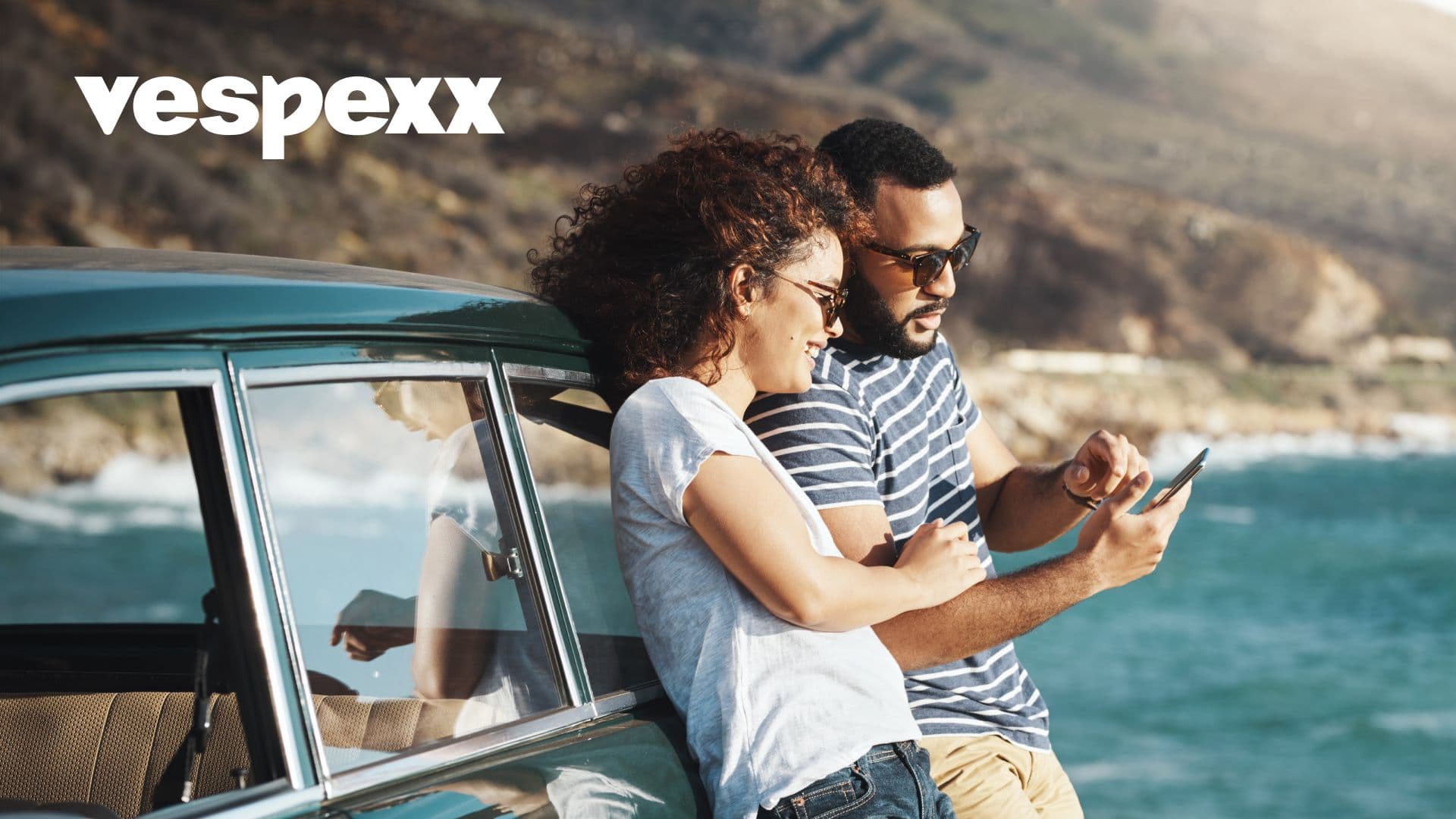 A young couple on a coastal vista use the vespexx app together, strengthening their relationship.